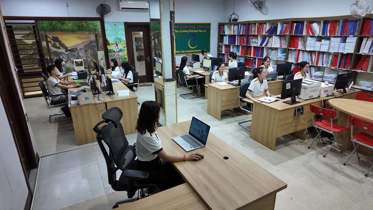 Văn phòng Tâm - Tầm - Tài với dãy bàn, kệ hồ sơ và nhân viên làm việc – Báo cáo tài chính năm