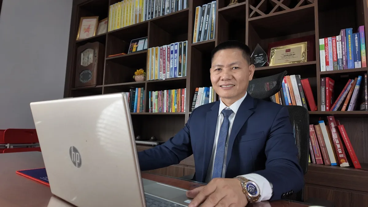 Anh Nguyễn Quốc Huy ngồi làm việc với laptop trước tủ sách tại Tâm - Tầm - Tài – Chi phí thành lập công ty tnhh 1 thành viên