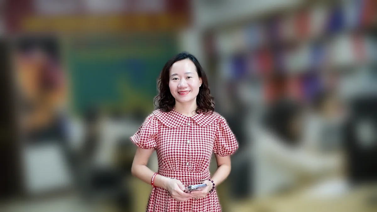 Chị Thảo Nguyễn mặc váy caro đỏ đứng cười tại văn phòng Tâm - Tầm - Tài – chia sẻ về đăng ký kinh doanh dạy thêm