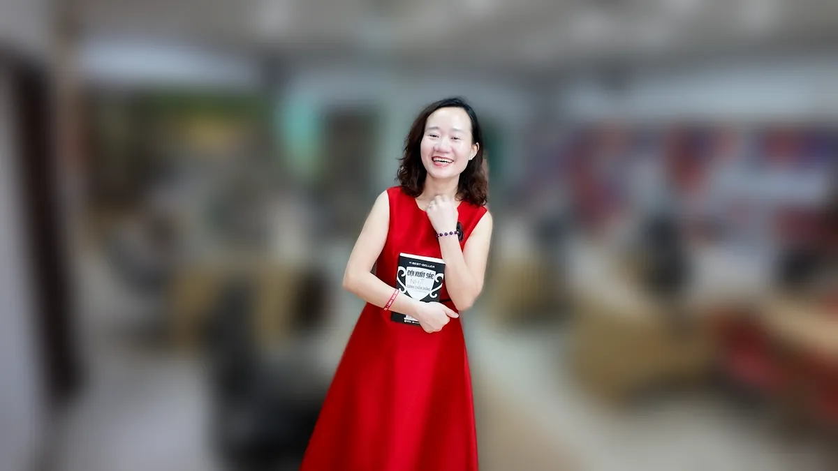 Chị Thảo Nguyễn váy đỏ đứng thẳng mỉm cười tại văn phòng Tâm - Tầm - Tài – chia sẻ về đặt tên công ty