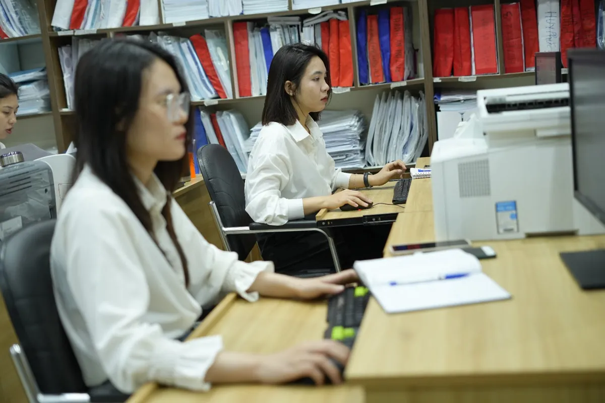 Nữ nhân viên áo trắng gõ máy tính cạnh sổ ghi chép tại Tâm - Tầm - Tài – Giáo viên dạy thêm có phải nộp thuế không