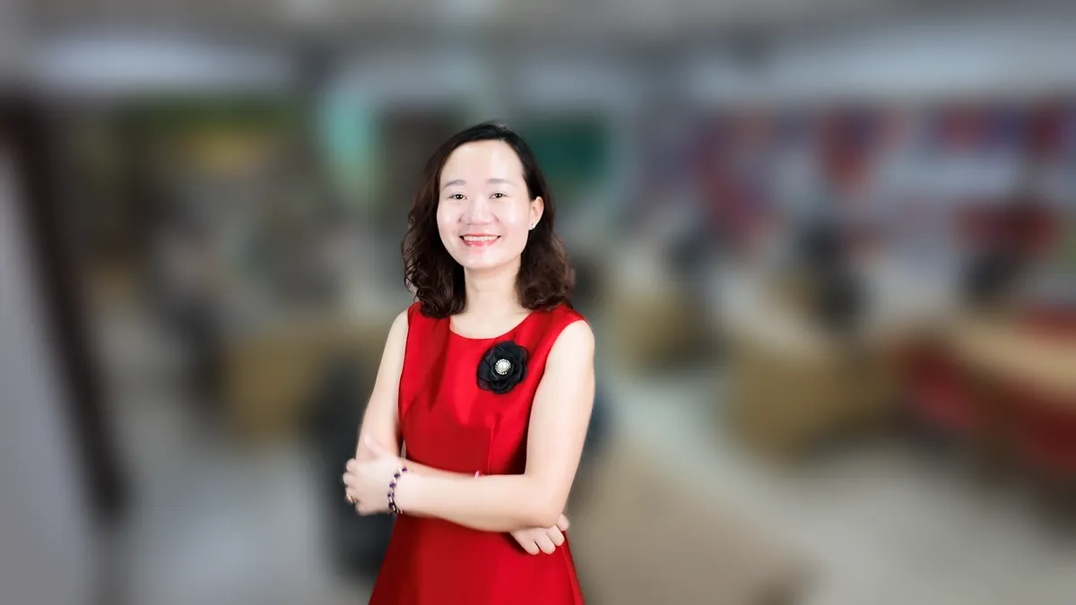 Chị Thảo Nguyễn váy đỏ chống hông, mỉm cười nhìn thẳng tại văn phòng Tâm - Tầm - Tài – chia sẻ về mở công ty cần bằng cấp gì