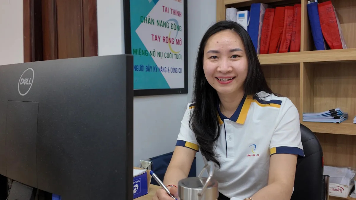 Nhân viên nữ ngồi bàn máy tính mỉm cười nhìn ống kính