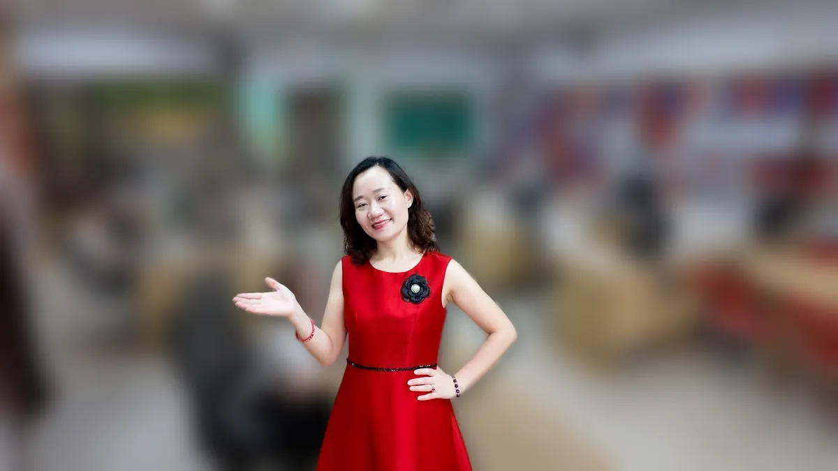 Chị Thảo Nguyễn váy đỏ đứng thẳng mỉm cười tại văn phòng Tâm - Tầm - Tài – chia sẻ về thành lập chi nhánh công ty