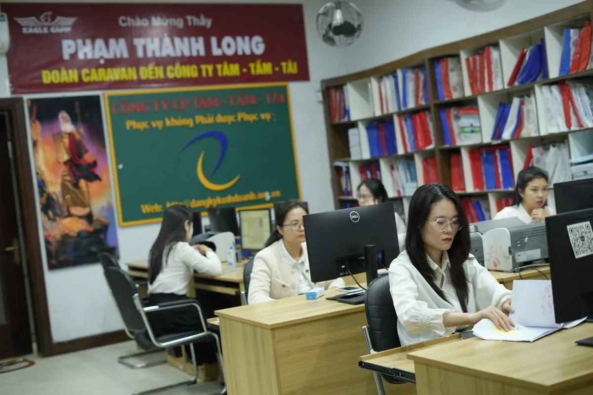 Nhân viên ngồi máy tính trong văn phòng, kệ hồ sơ đầy