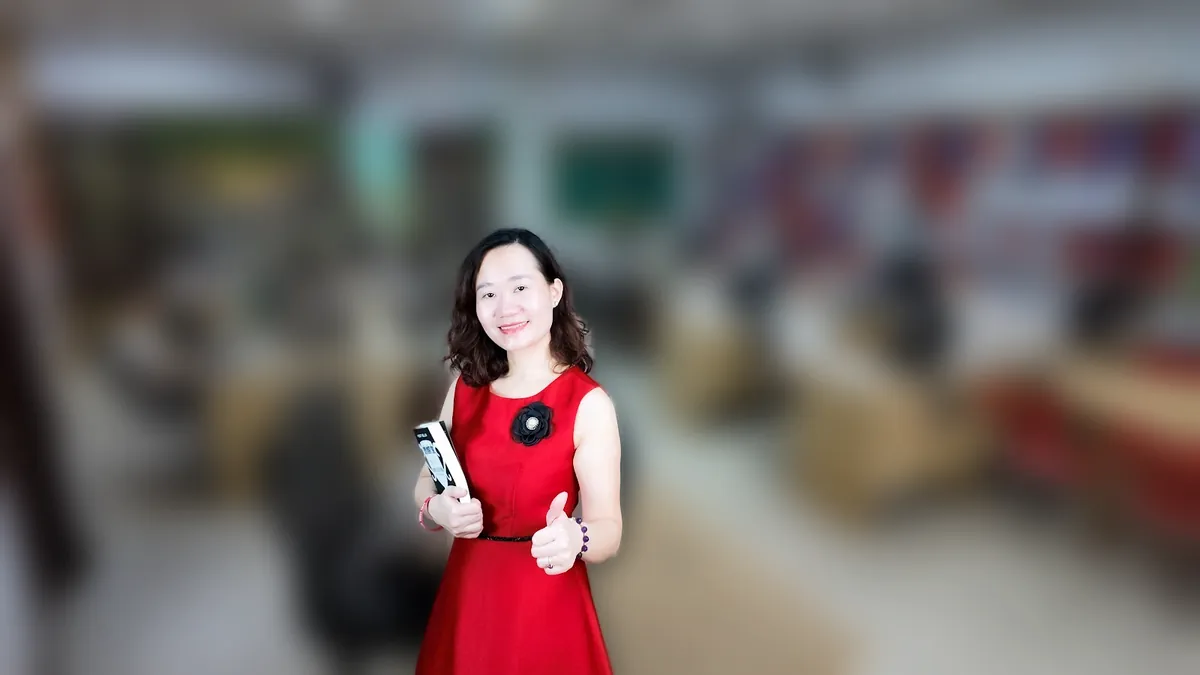 Chị Thảo Nguyễn váy caro đỏ đưa hai tay như giới thiệu, mỉm cười tại văn phòng Tâm - Tầm - Tài – chia sẻ về thảo nguyễn tâm tầm tài