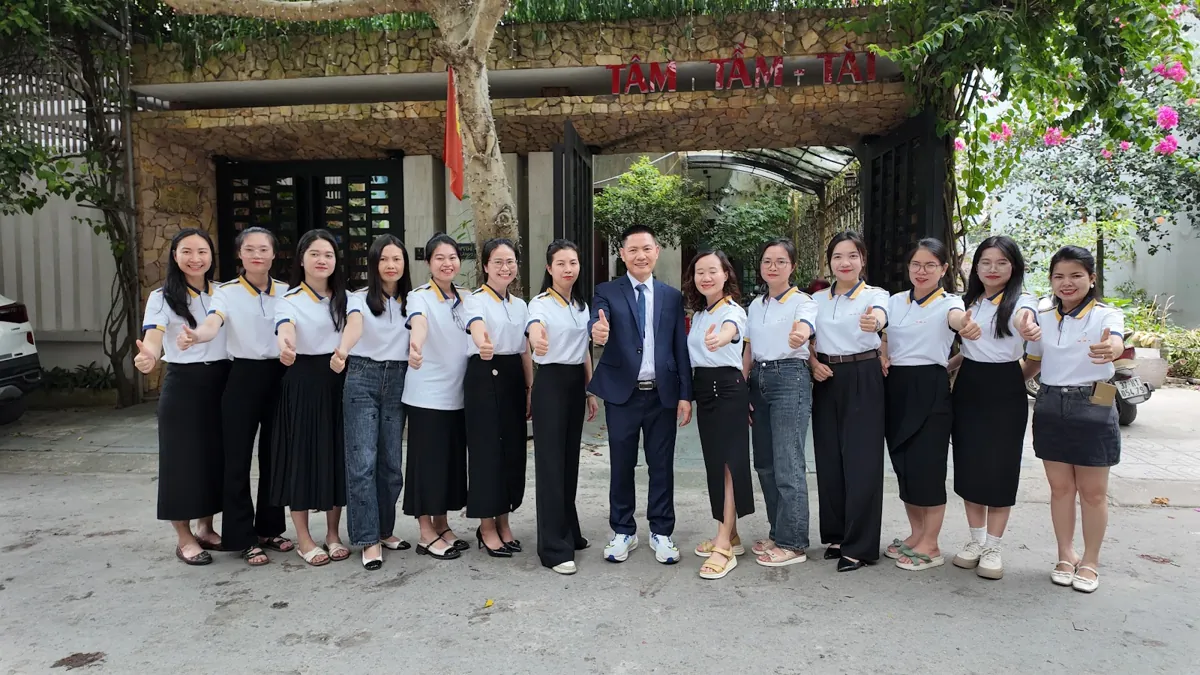 Ảnh tập thể đội ngũ trước cổng có biển Tâm - Tầm - Tài